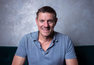 Simon Cabot sitting and smiling at camera.